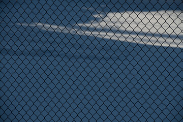Chain link fence reflecting light from sun snow in background horizontal format background or wallpaper