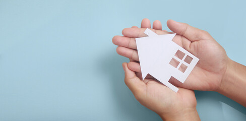 Hands holding paper house, family home  protecting insurance concept