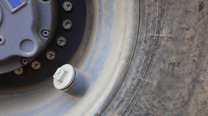 Tire valve on the rim of the tire. On the background of the tires, scrape a large road with a copy area. Close focus and select an object