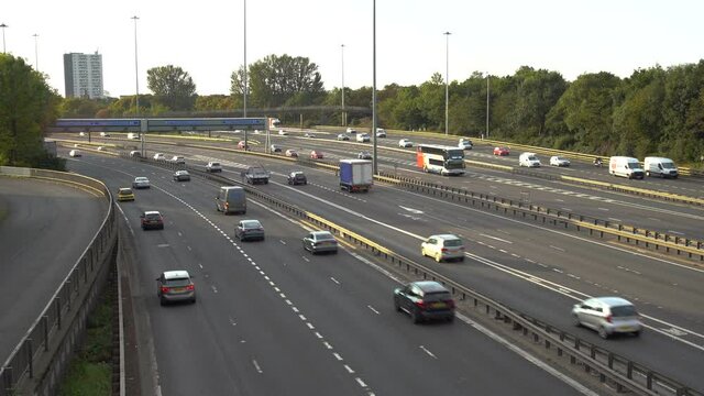 Vehicles driving on a motorway on highway M8 of the ring of Glasgow on a bright summer day. Wide steady shot