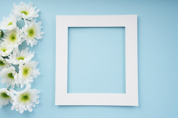 Mock up white frame with flower over bright blue background.