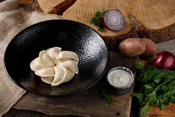 Appetizing traditional Russian dumplings, hand-made with potatoes. Still life on a wooden board. Close-up.