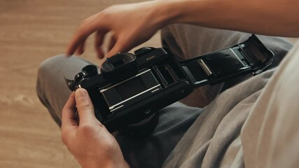 Person loading film into 35mm camera while sitting