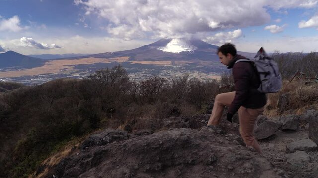 Male hiker sitting down on top of mountain for break, Mt Fuji in background