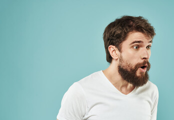 Fototapeta premium Guy in a white t-shirt brunet on a blue background cropped view puzzled look side view