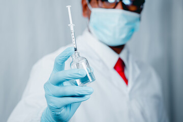 Doctor or scientist wearing antivirus clothing In the laboratory, research laboratories are studying and developing a medical vaccine, COVID-19, holding a syringe with a liquid vaccine.