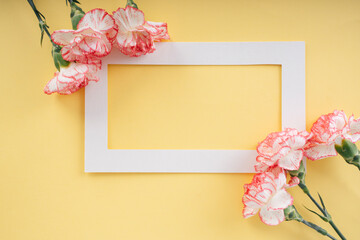 White mock up with carnation flower over yellow background.