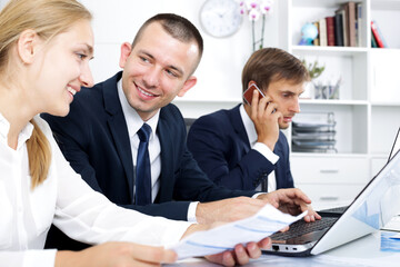 Portrait of three happy business colleagues working and discussing working task on phone in office. Focus on the man