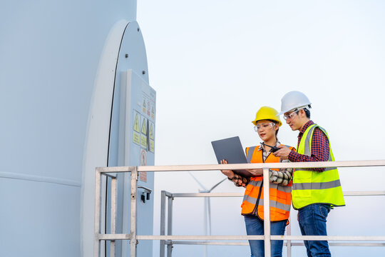 engineer team working with laptop computer against wind turbine farm
