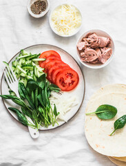 Ingredients for making quesadillas - canned tuna, vegetables, cheese and tortillas on a light background, top view