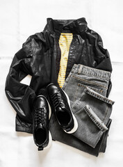 Women's clothing - yellow cotton striped t-shirt, gray mom jeans, black windbreaker and black leather sneakers on a light background, top view © okkijan2010