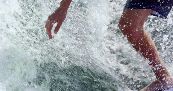 Man wake surfing - close up on hand balancing against the wave