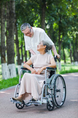 The old man pushes his wife in a wheelchair