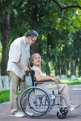 The old man pushes his wife in a wheelchair