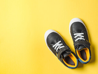 pair of new kids or adult sneakers on yellow background, top view. Flat lay gray and yellow or...