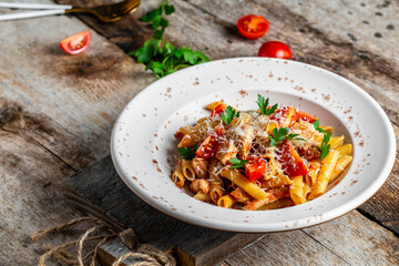 Penne pasta with chili sauce arrabiata. Classic italian penne arrabiata with chicken, tomatoes, cheese parmesan on a rustic wooden table. Food recipe background. Close up