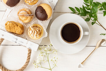 Morning cup of coffe with tasty freshly baked desserts decorated with leaves and flowers. Light and airy backdrop