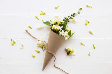 white flowers jasmine local of asia in brown paper cone arrangement flat lay postcard style on background white wooden