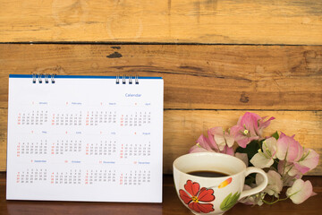 calendar yearly planner for business work with pink flower and hot coffee on table at office desk