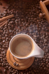 cup of coffee and coffee beans in a sack on dark background, top view