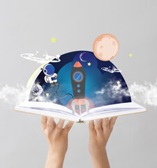 Hands holding book with drawn magic world on grey background