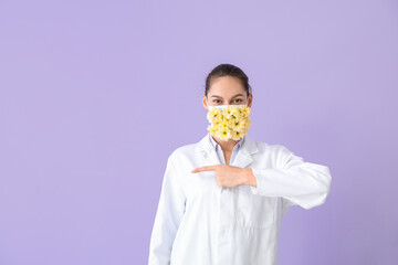 Allergist in facial mask with flowers pointing at something on color background