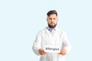 Doctor holding paper with word ALLERGIST on color background