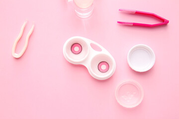 Bottle of solution, tweezers and container with contact lenses on color background