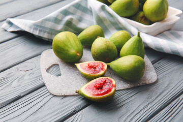 Board with fresh green figs on wooden background