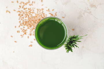 Glass with fresh wheatgrass juice on light background