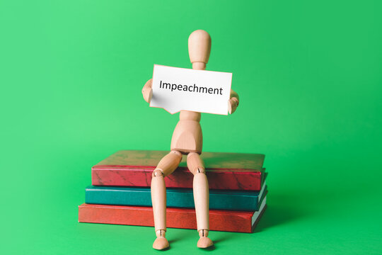 Books and wooden mannequin holding paper with word IMPEACHMENT on color background - Powered by Adobe
