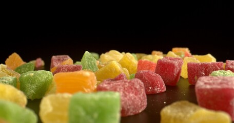A mound of colored dried fruits on a black reflective surface of table. Healthy natural sweets....