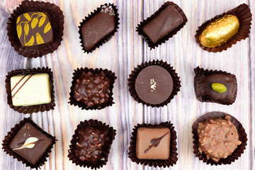 Chocolates from a gift set in corrugated paper baskets, laid out in three rows on a wooden surface