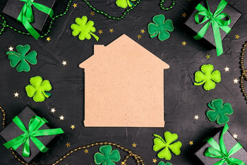 Home symbol surrounded by gifts, four-leaf clover and stars on black background. Copy space....