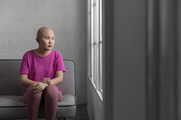 Portrait of sad Asian woman cancer patient after suffering serious hair loss due to chemotherapy