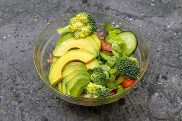 Green salad with avocado, cucumber, broccoli, and lettuce. Healthy organic vegan salad.