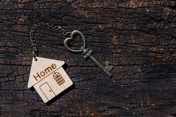 Fototapeta na wymiar House key with home keyring decorated with mini heart on rusty wood background