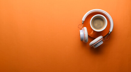 A cup of coffee, headphone and copy space on orange background.
