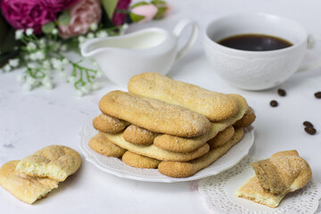Biscuit cookies savoyardi, coffee and flowers on a white marble background