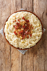 Tasty Estonian mashed potatoes and barley with onions and bacon close-up in a plate on the table. Vertical top view from above
