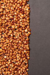 Background of peeled Siberian pine nuts on a dark gray background. 