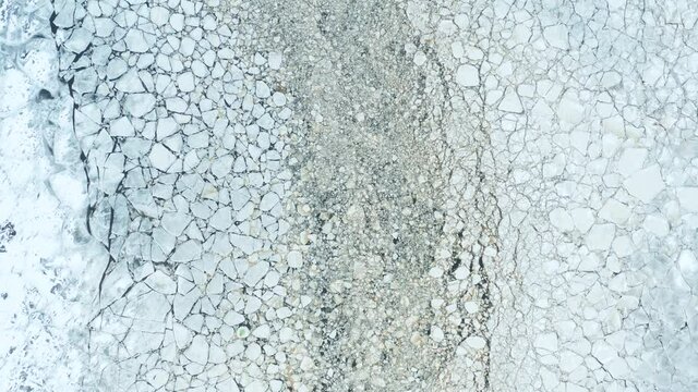 Aerial fly over view of cracked ice floes floating in the sea. Densely dispersed pieces.  Contrast between large and small floes. Forward camera movement. 4k footage.