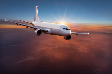 Fototapeta na wymiar Commercial airplane jetliner flying above dramatic clouds in beautiful light. Travel concept.