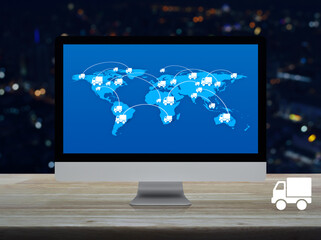 Delivery truck icon with connection line and world map on modern computer monitor screen on wooden table over blur colorful night light city tower and skyscraper, Business transportation online concep