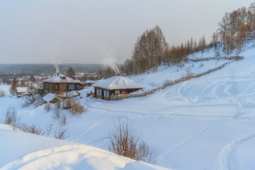 A panoramic view of the winter provincial Cherdyn (Northern Urals, Russia) - a city on several hills where people go skiing. wooden houses with smoke coming out of pipes, pure snow