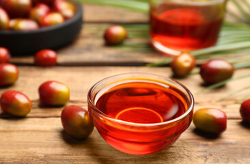 Palm oil in glass bowl, tropical leaf and fruits on wooden table