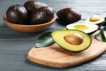 Whole and cut avocados on grey wooden table
