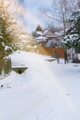 Snowy road between houses and cottages. Endless snowstorms can interrupt traffic. It snows and freezes a lot. The road are covered with snow and frost.
