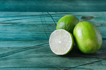 fresh green limes and half a lime on a wooden background of kopi space	