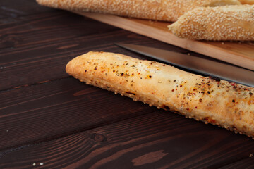 Baguette bread on brown wooden board close up